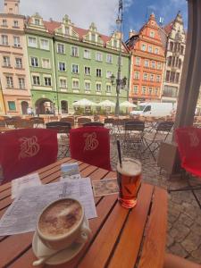 a table with a cup of coffee and a glass of beer at Heart of the Old WROCLOVE in Wrocław
