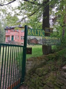 płot z różowym budynkiem za drzewem w obiekcie Baltic Home w Polanicy Zdroju