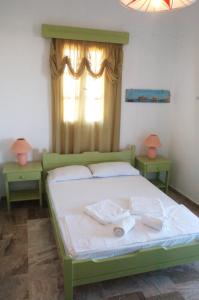 1 Schlafzimmer mit einem grünen Bett und 2 Tischen in der Unterkunft Miltiadis Apartments in Ampelas