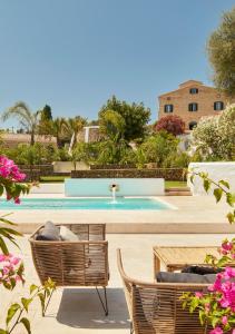 a swimming pool with two chairs and a table at Agroturismo Rafal Rubí in Alaior