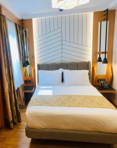 um quarto com uma cama grande e almofadas brancas em Maywood Hotel em Istambul
