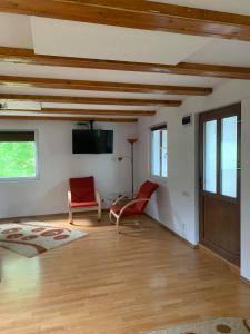 a living room with wooden ceilings and red chairs at Casa ANA in Geoagiu