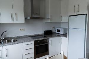 a kitchen with white cabinets and a white refrigerator at Casa Area da Vila in Camariñas +10 photos