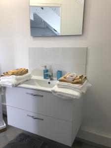 Baño blanco con lavabo y espejo en Appartement T2 meublé, en Saint-Quentin
