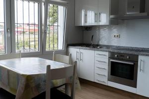 a kitchen with white cabinets and a table and a window at Casa Area da Vila in Camariñas