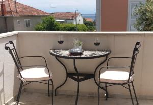 uma mesa com 2 cadeiras e copos de vinho numa varanda em Apartmani Goran Orebić em Orebić