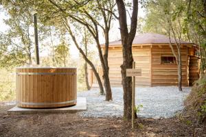 una cabaña de madera con un cubo de basura junto a un árbol en Nits de Bosc, en Vilassar de Dalt