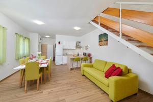 a living room with a yellow couch and a dining room at Apartment Olivix in Pula