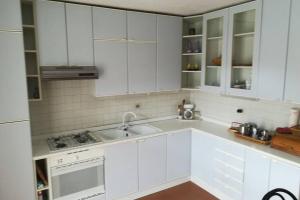 a white kitchen with white cabinets and a sink at Casa bianca in Malè