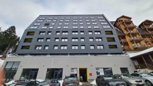 un edificio alto con auto parcheggiate in un parcheggio di Mountain Angel Apartment a Jahorina