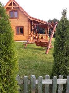 een blokhut met een veranda en een houten hek bij Domek nad jeziorem Ublik in Miłki