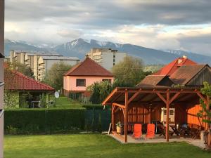 a gazebo with orange chairs in a yard with mountains at Apartman Emka 2 in Liptovský Mikuláš