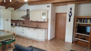 una cucina con armadi bianchi, tavolo e TV di Cesa Stefi a Canazei