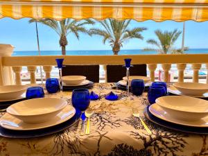 een tafel met borden en wijnglazen op een balkon bij Apartamento frente al mar en El Campello in El Campello