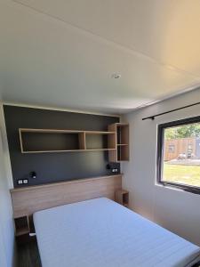 Mobil Home XXL2 4 chambres - Camping Bordeaux Lac في Bruges: غرفة نوم صغيرة بها سرير ونافذة