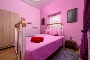 Dormitorio rosa con cama con almohada roja en Villa Kontesa Kamara Corfu en Kamára