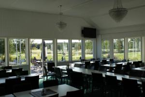 a dining room with tables and chairs and windows at Piteå Golfhotell in Piteå