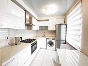 cocina con armarios blancos, lavadora y secadora en 2-bedroom apartment Most City Area, Ekaterynoslav square, en Dnipro
