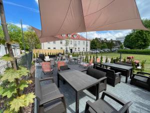 a patio with tables and chairs and an umbrella at Apartamenty Park in Ciechocinek