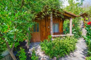 a wooden cabin with a porch in a garden at Agora Pansiyon in Kapıkırı