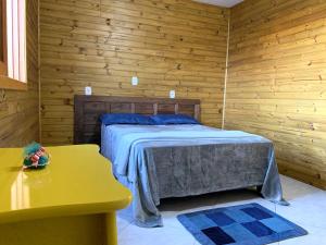 ein Schlafzimmer mit einem Bett in einem Holzzimmer in der Unterkunft Chalé no centro da Capital dos Canyons in Praia Grande