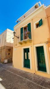 een geel gebouw met groene deuren en een balkon bij Antica Casa Tabarkina in Carloforte