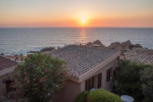 uma vista para uma casa com o pôr-do-sol ao fundo em Casa del Tramonto Costa Paradiso em Costa Paradiso