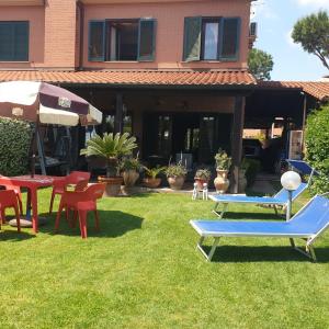 - une cour avec des chaises, des tables et un parasol dans l'établissement luxury 3-Bedrooms villa near the sea in Rome, à Rome