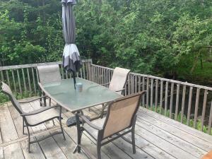 una mesa y sillas en una terraza con sombrilla en Camping Chalets Spas Pignons Rouges, en Saint Romain