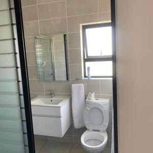 a bathroom with a toilet and a sink and a mirror at THE BLYDE CRISTAL LAGOON in Pretoria