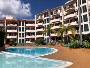 フンシャルにあるVarandas do Funchalの大きなアパートメントの建物の前にスイミングプールがあります。