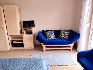a living room with a blue couch and a tv at Libis Apartman in Bük