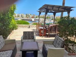 eine Terrasse mit Stühlen, einem Tisch und einem Sonnenschirm in der Unterkunft chalet1 ch21 with a wonderful view 2 bed rooms terrace and garden green beach in El-Alamein