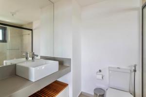 uma casa de banho branca com um lavatório e um WC em Ioda Guesthouse em Arraial do Cabo