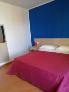 a bedroom with a bed with a pink blanket on it at Tus'Hotel in Castel di Tusa