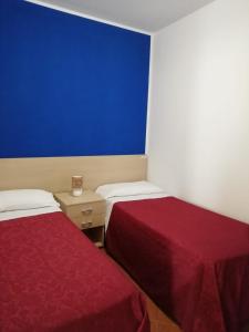 a room with two beds and a blue wall at Tus'Hotel in Castel di Tusa