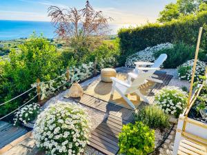 un jardín con 2 sillas blancas y flores en Residenza B&B VistaMare, en Petacciato