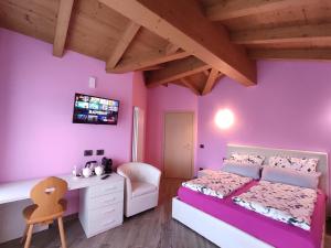 1 dormitorio con paredes de color púrpura, 1 cama y escritorio en B&B Il Germoglio en Castione Andevenno
