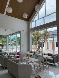 a restaurant with tables and chairs and large windows at Busaba Bella Hotel in Sichon
