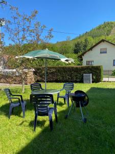 a table and chairs with an umbrella and a grill at Appartement à Mitzach in Mitzach