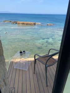 a glass table and a chair on a deck with the ocean at The Tanneries Hotel & Spa in Chania