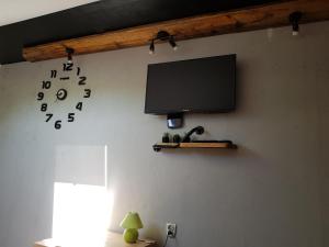 a flat screen tv hanging on a wall with a clock at Na Stawach in Stryszów