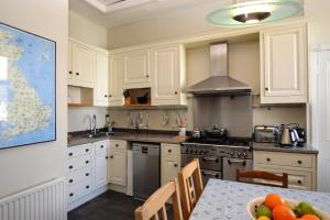 a kitchen with white cabinets and a table with a bowl of fruit at Kimberley Apartment in Dunoon