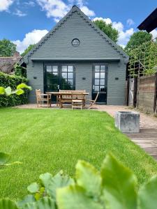 una casa con una mesa de picnic en un patio en The Green House Lodge en Den Dungen