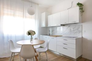 cocina con armarios blancos, mesa y sillas en Tommy's Flat en Mestre