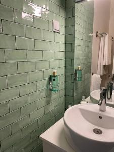 ein Badezimmer mit einem weißen Waschbecken und einer grün gefliesten Wand in der Unterkunft Arcos 61 in Tomar + 32 Fotos