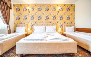een slaapkamer met 2 bedden en een gele muur bij Penzión Heléné in Veľký Meder