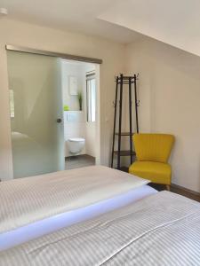 1 dormitorio con 1 cama y 1 silla amarilla en Pension / Ferienwohnungen Scheid, en Kestert