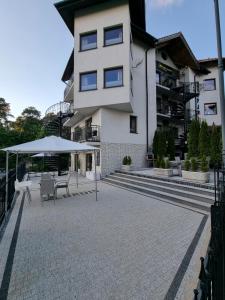 a building with a patio with tables and an umbrella at Villa Lordis in Krynica Morska