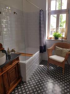 a bathroom with a shower and a tub and a chair at Belvárosi Kertesház in Keszthely +52 photos